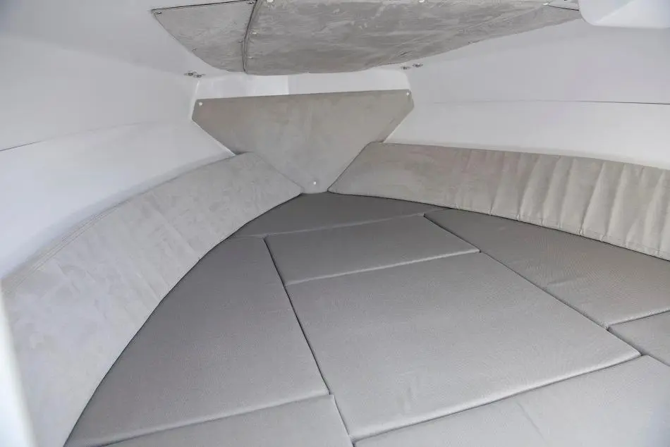Interior of a boat cabin featuring grey cushions and a simple, streamlined design for comfortable resting space.